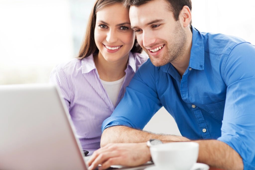 youing smiling couple looking at computer and setting up a new online hustle